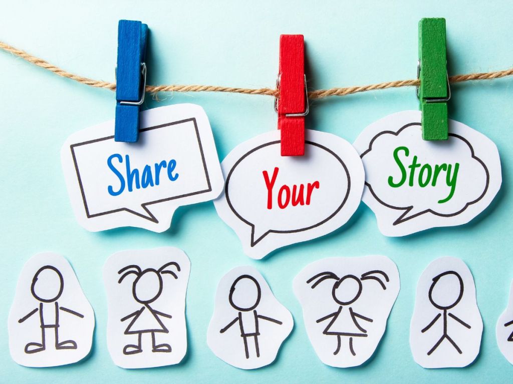 There is a light blue background with a string-like clothes line with different color clothes pins holding up separate cutout paper words saying, "Share your story." Below that are paper cutout stick figures of men and women.