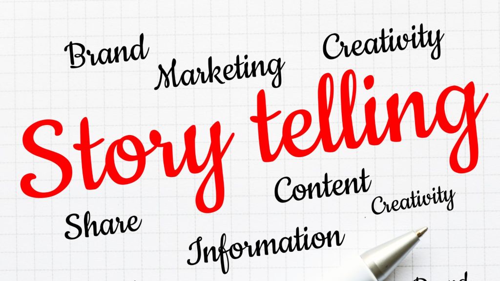 Photo of graph paper with the word Storytelling written in large red type. Other words around storytelling include: brand, marketing, creativity, share, information, content, and creativity. The other words are in black.