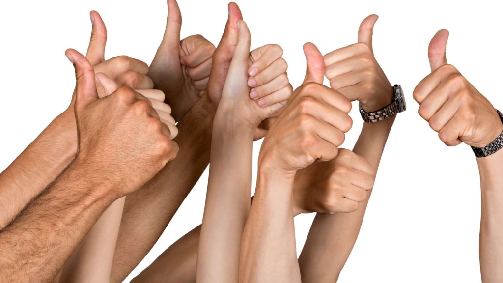 There are ten hands in the air against a white background all giving thumbs up. Some of them have watches and rings on. This is to show that it's ok to show up and share your story.