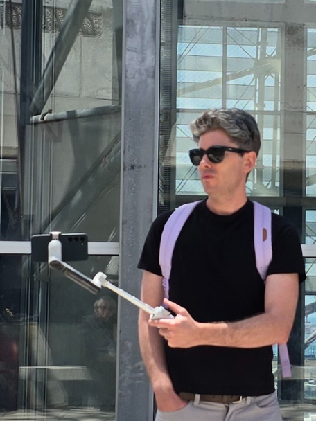 Matthew using his phone to record footage on a gimbal at the top floor of the Downtown San Diego Central Library near their art gallery.
